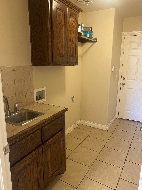 1405 NW 13th Place, Moore, OK 73170 laundry room featuring sink, hookup for an electric dryer, washer hookup, light tile floors, and cabinets
