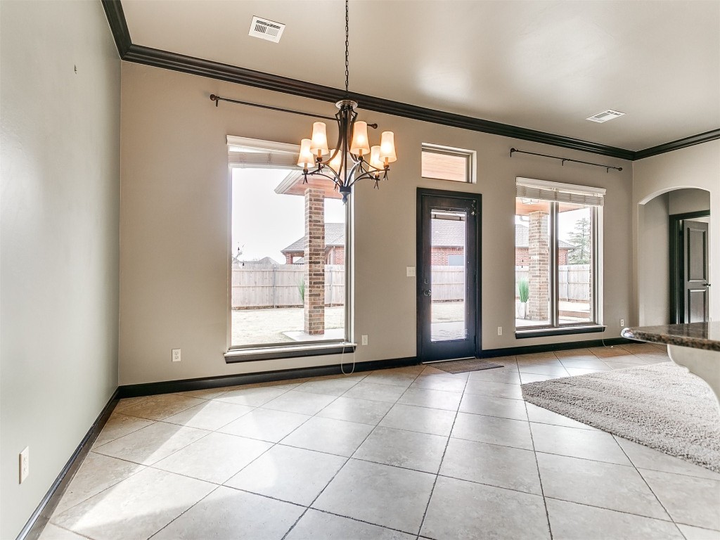 4708 NW 153rd Street, Edmond, OK 73013 kitchen featuring a wealth of natural light, crown molding, ceiling fan with notable chandelier, and a fireplace