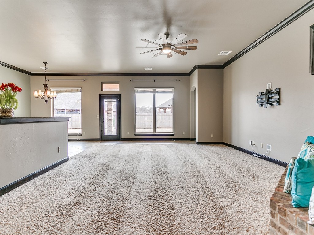 4708 NW 153rd Street, Edmond, OK 73013 unfurnished living room with ornamental molding, a brick fireplace, light colored carpet, and ceiling fan