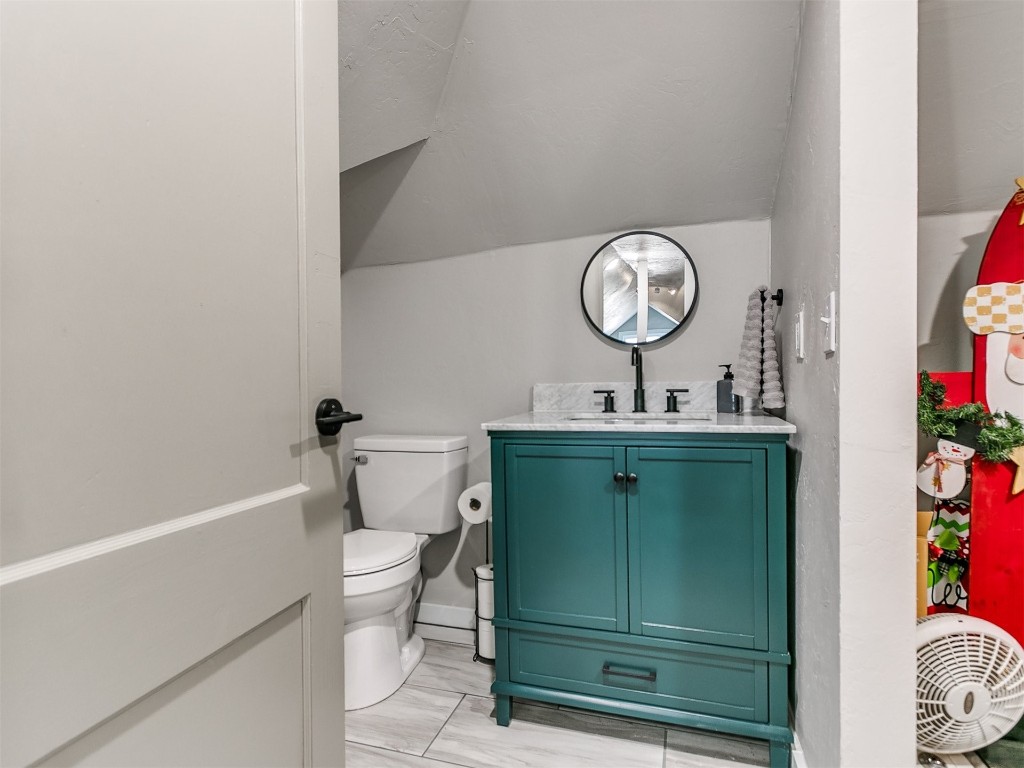 804 E Noble Avenue, Guthrie, OK 73044 bathroom featuring vanity, toilet, tile flooring, and lofted ceiling