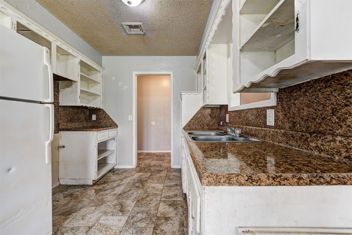 8709 N Hudson Avenue, Oklahoma City, OK 73114 kitchen with a textured ceiling, white fridge, white cabinets, light tile floors, and backsplash