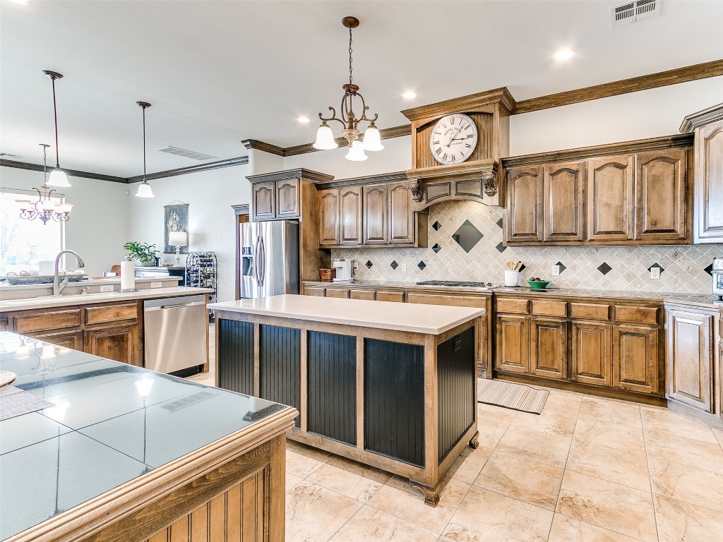 4610 Pikeys Trail, Tuttle, OK 73089 kitchen with tasteful backsplash, appliances with stainless steel finishes, a notable chandelier, pendant lighting, and a center island