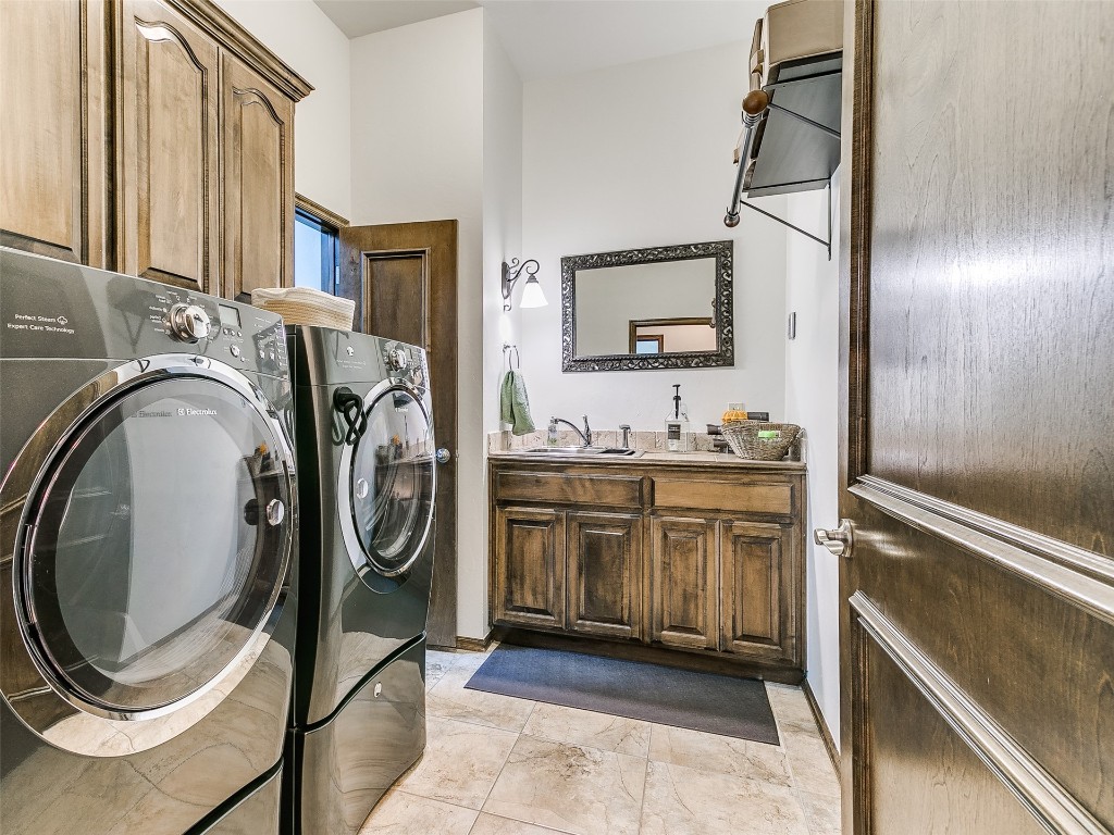 4610 Pikeys Trail, Tuttle, OK 73089 laundry room featuring light tile floors, washer and dryer, sink, and cabinets
