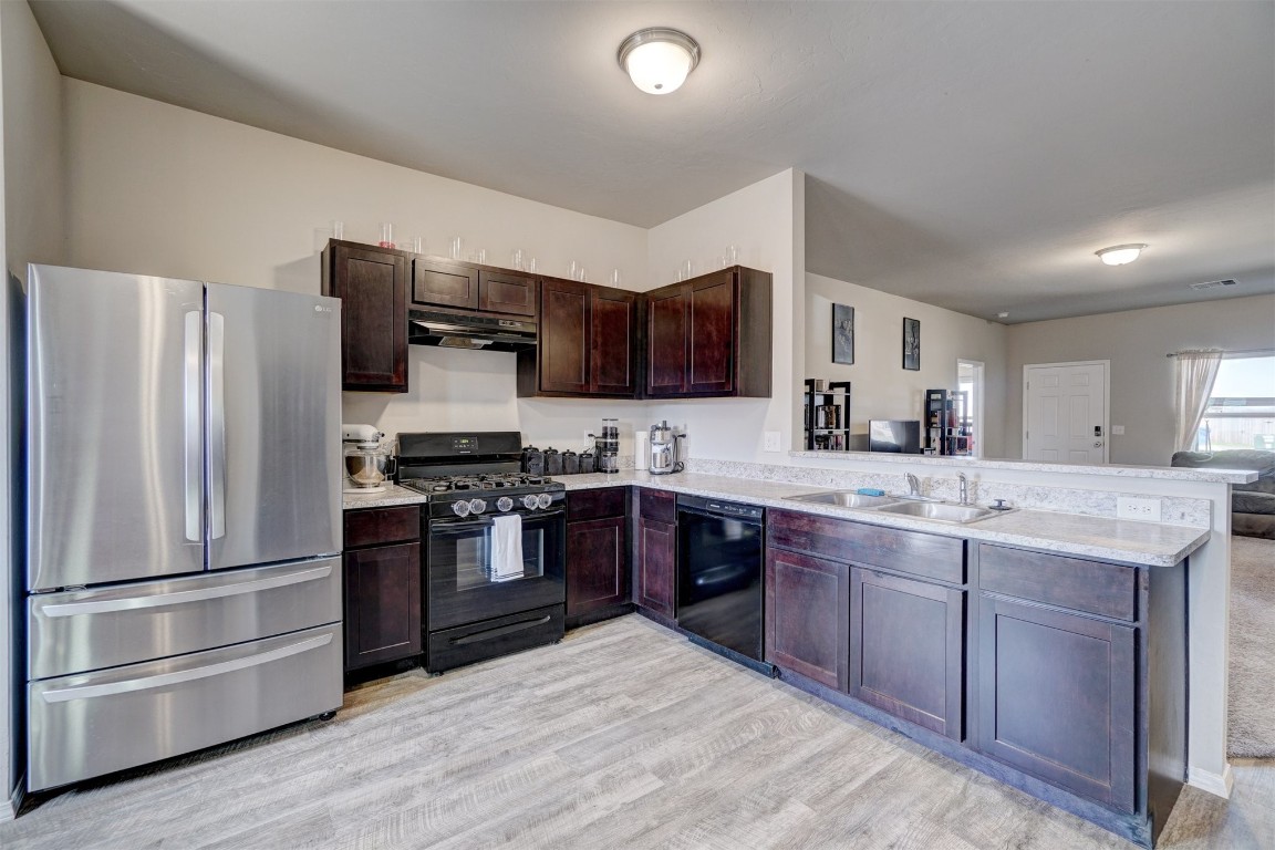 1316 Peridot Lane, Noble, OK 73068 kitchen featuring black appliances, sink, light hardwood / wood-style flooring, dark brown cabinets, and kitchen peninsula