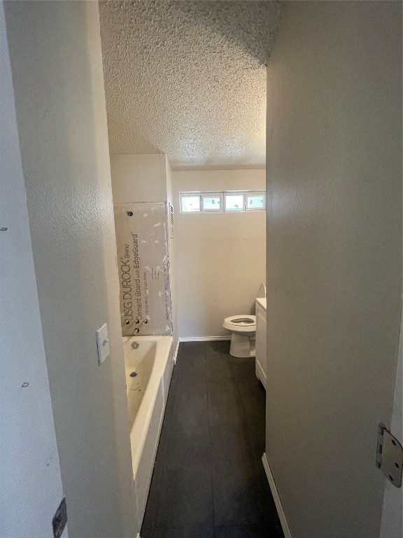 4017 SE 46th Street, Oklahoma City, OK 73135 bathroom with tile flooring, a bathing tub, a textured ceiling, and toilet