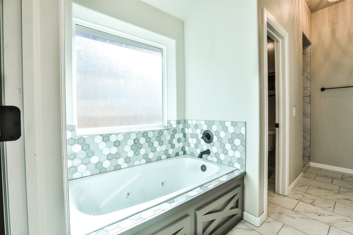 12017 SW 50th Street, Mustang, OK 73064 bathroom featuring a bathtub, plenty of natural light, and tile floors