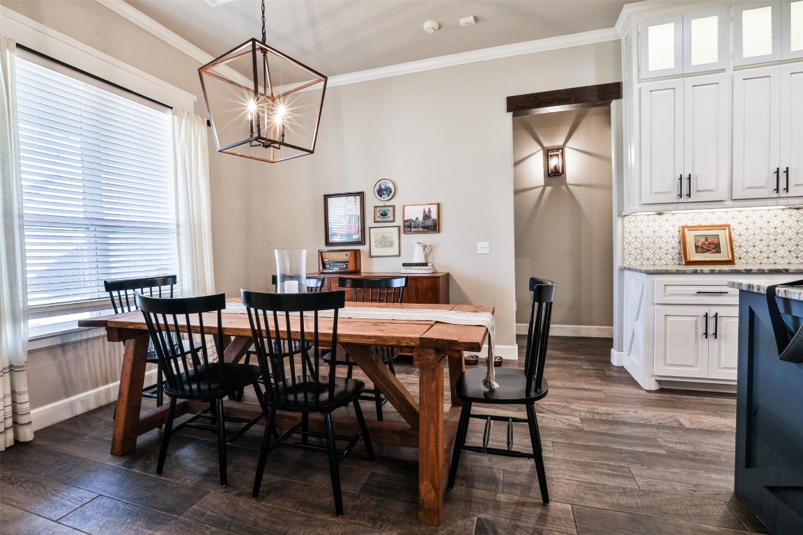 12017 SW 50th Street, Mustang, OK 73064 dining area featuring a wealth of natural light, a chandelier, crown molding, and dark hardwood / wood-style floors