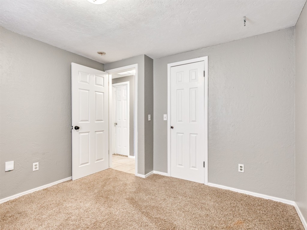 8416 NW 92nd Street, Oklahoma City, OK 73132 unfurnished bedroom featuring a textured ceiling, a closet, and light colored carpet