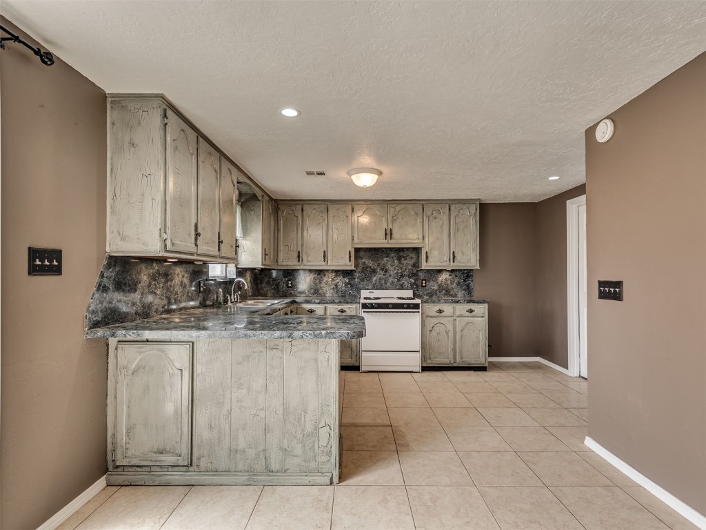8416 NW 92nd Street, Oklahoma City, OK 73132 kitchen featuring light tile floors, white range oven, kitchen peninsula, and backsplash
