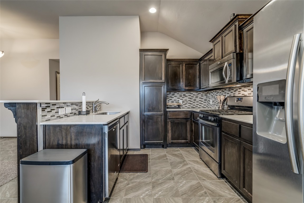 2561 NW 186th Street, Edmond, OK 73012 kitchen featuring backsplash, light tile floors, stainless steel appliances, and dark brown cabinets