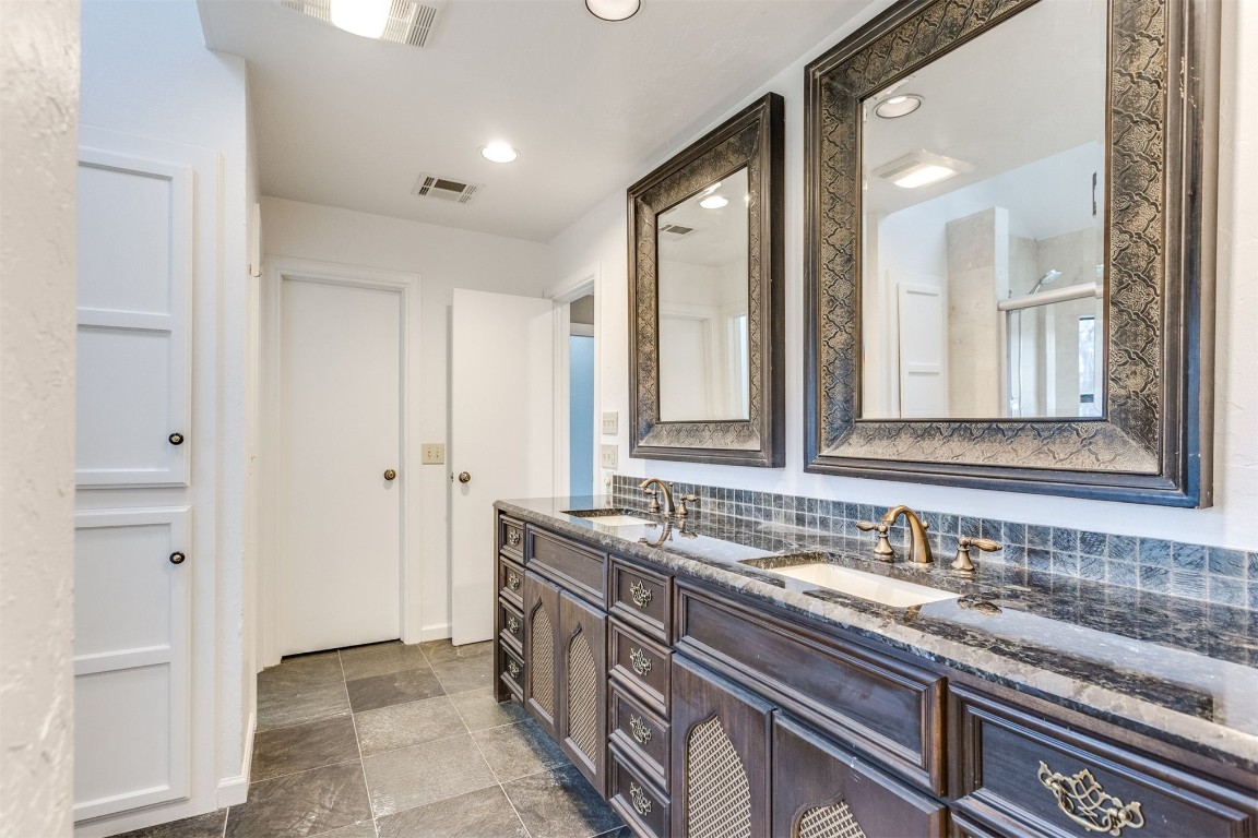3904 Spyglass Road, Oklahoma City, OK 73120 bathroom featuring dual sinks, vanity with extensive cabinet space, tile flooring, and tasteful backsplash