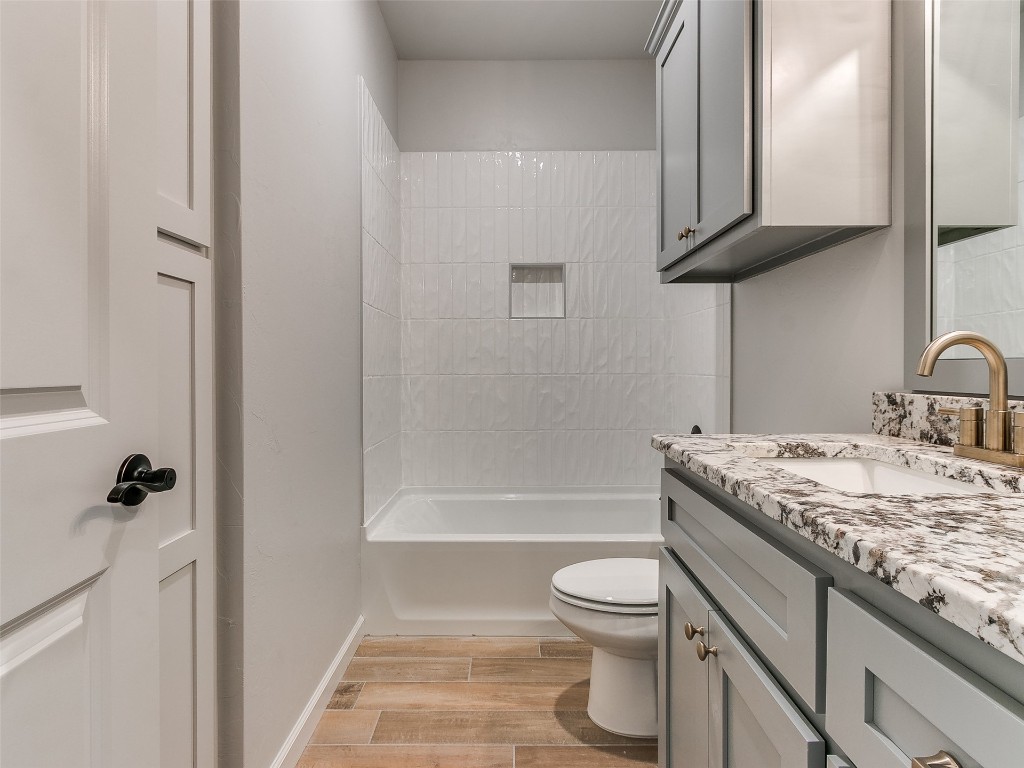 12105 SW 51st Street, Mustang, OK 73064 full bathroom with wood-type flooring, oversized vanity, tiled shower / bath combo, and toilet