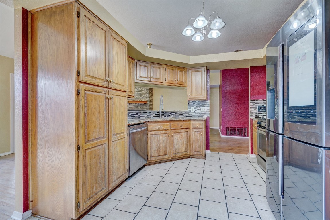 11440 Walters Avenue, Oklahoma City, OK 73162 kitchen with tasteful backsplash, sink, light hardwood / wood-style flooring, a chandelier, and stainless steel appliances