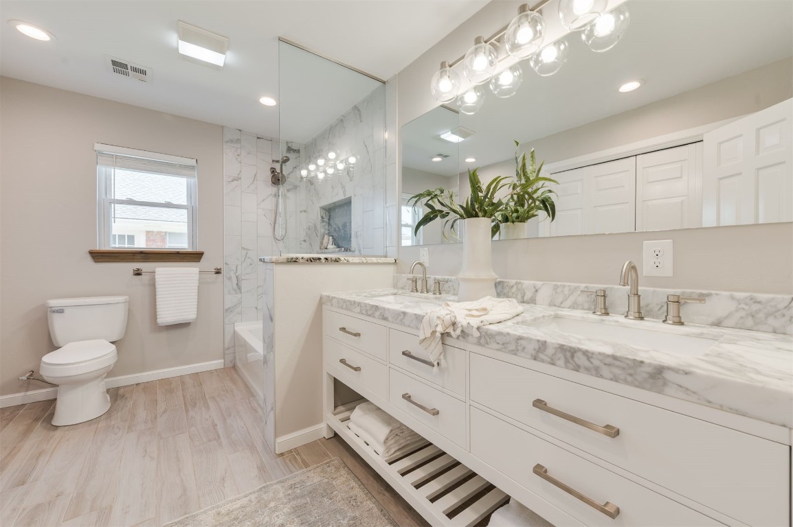 3108 Huntleigh Drive, Oklahoma City, OK 73120 full bathroom with dual vanity, toilet, hardwood / wood-style flooring, and tiled shower / bath combo
