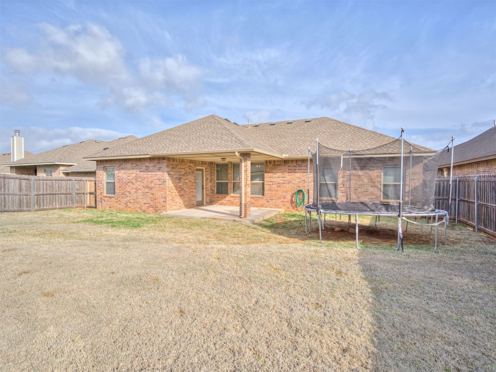 8208 NW 160th Terrace, Edmond, OK 73013 rear view of house with a lawn, a patio area, and a trampoline