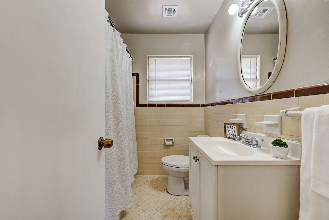 3022 NW 20th Street, Oklahoma City, OK 73107 bathroom featuring backsplash, tile walls, tile flooring, oversized vanity, and toilet