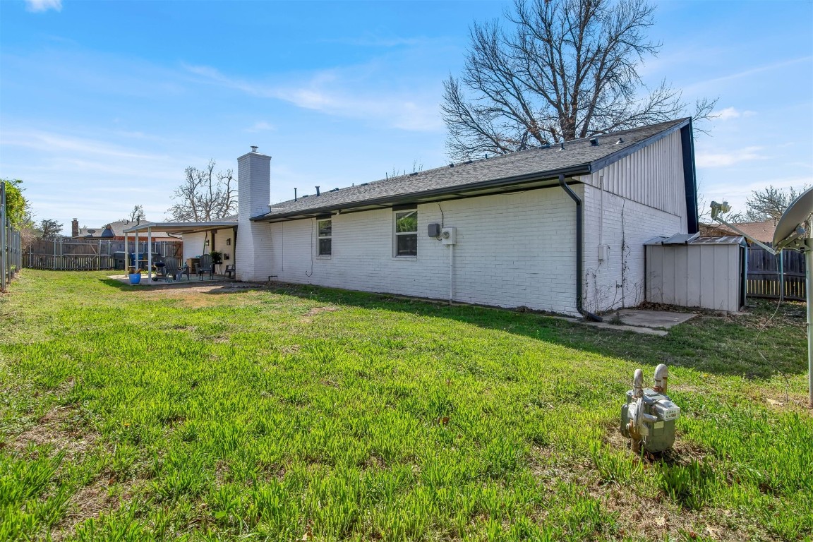 3012 Robin Road, Midwest City, OK 73110 back of house with a storage unit, a lawn, and a patio