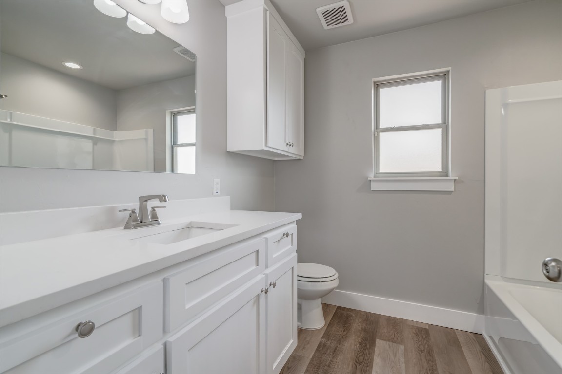 1525 NE 34th Street, Oklahoma City, OK 73111 full bathroom featuring vanity, toilet, bathtub / shower combination, and hardwood / wood-style floors