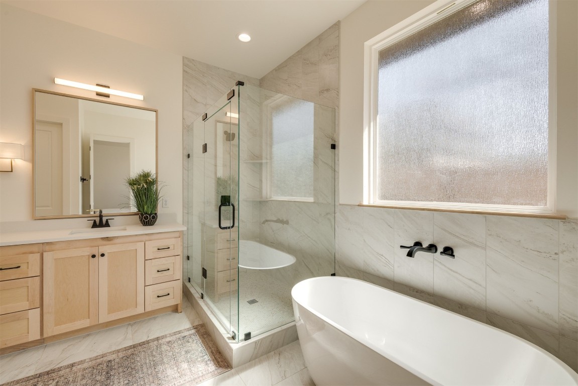 7124 Sunset Sail Avenue, Edmond, OK 73034 bathroom featuring tile flooring, independent shower and bath, tile walls, and vanity