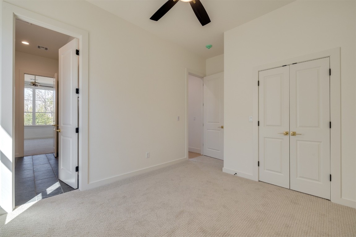 7124 Sunset Sail Avenue, Edmond, OK 73034 unfurnished bedroom with light tile floors, a closet, and ceiling fan