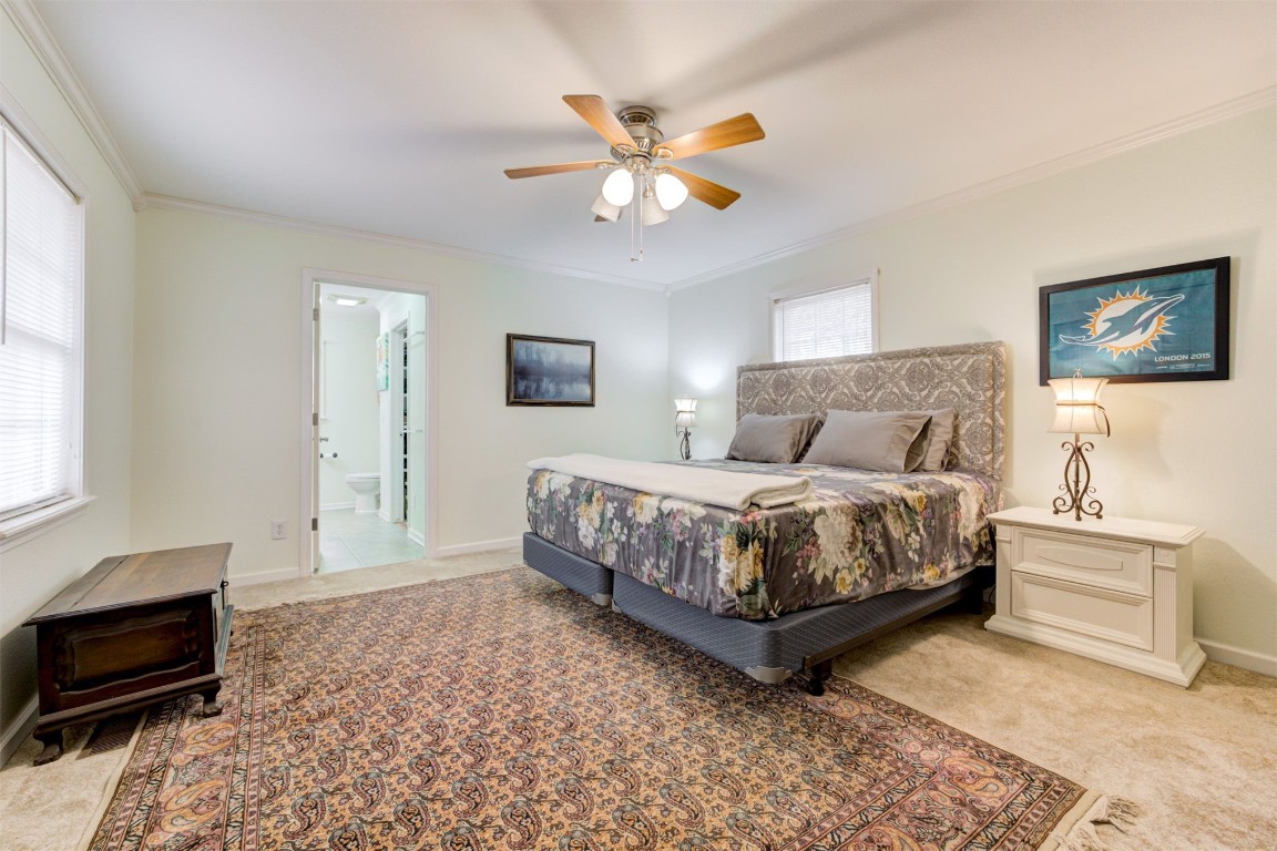 10774 S Pine Street, Guthrie, OK 73044 carpeted bedroom with multiple windows, ornamental molding, and ceiling fan
