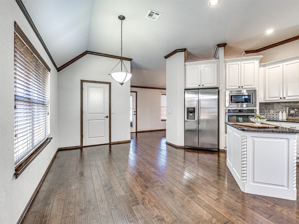 13512 Borgata Lane, Oklahoma City, OK 73170 kitchen with white cabinets, ornamental molding, stainless steel appliances, dark hardwood / wood-style floors, and hanging light fixtures