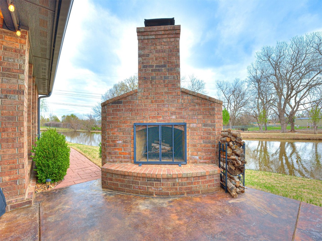 12600 SW 24th Street, Yukon, OK 73099 view of patio with a water view and an outdoor brick fireplace