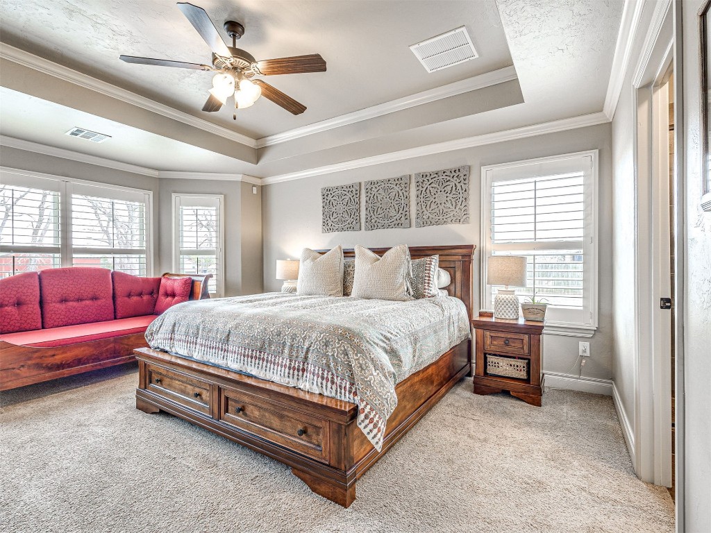 12600 SW 24th Street, Yukon, OK 73099 carpeted bedroom featuring a tray ceiling, crown molding, and ceiling fan