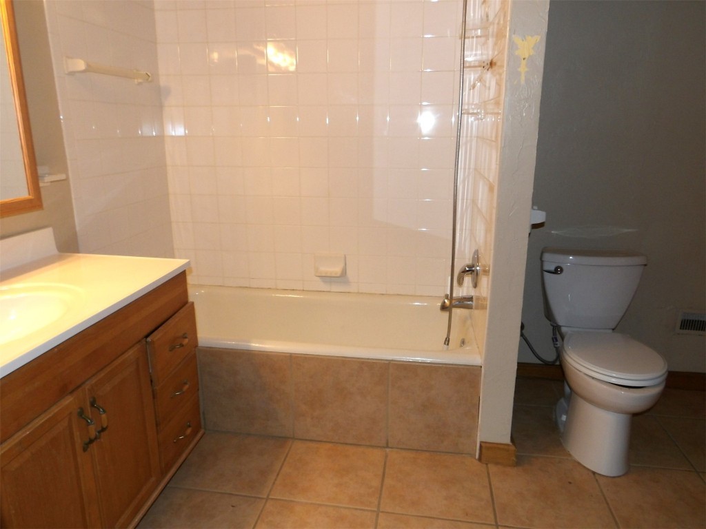 225 NW 1st Street, Moore, OK 73160 full bathroom with tiled shower / bath combo, toilet, tile floors, and vanity