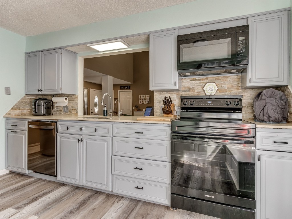 10511 Jeri Place, Oklahoma City, OK 73162 kitchen with light hardwood / wood-style flooring, electric range oven, dishwasher, and backsplash
