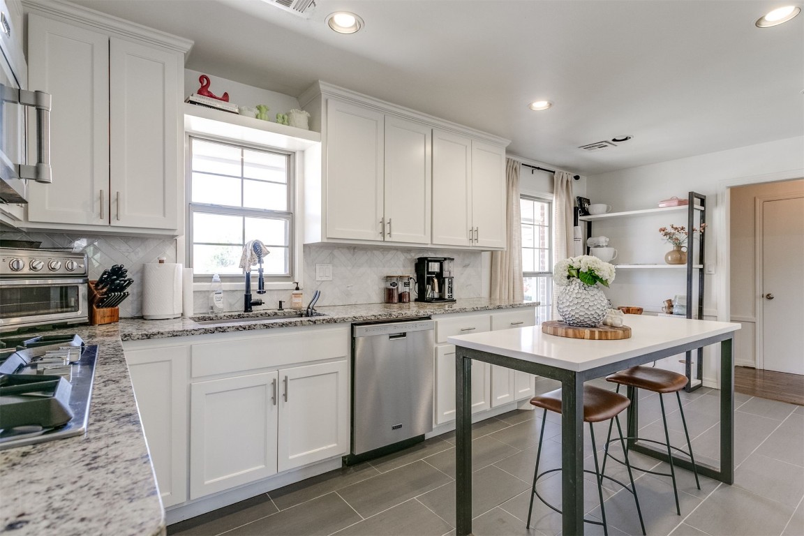 1504 Brighton Avenue, Oklahoma City, OK 73120 kitchen featuring backsplash, white cabinetry, stainless steel dishwasher, and tile flooring