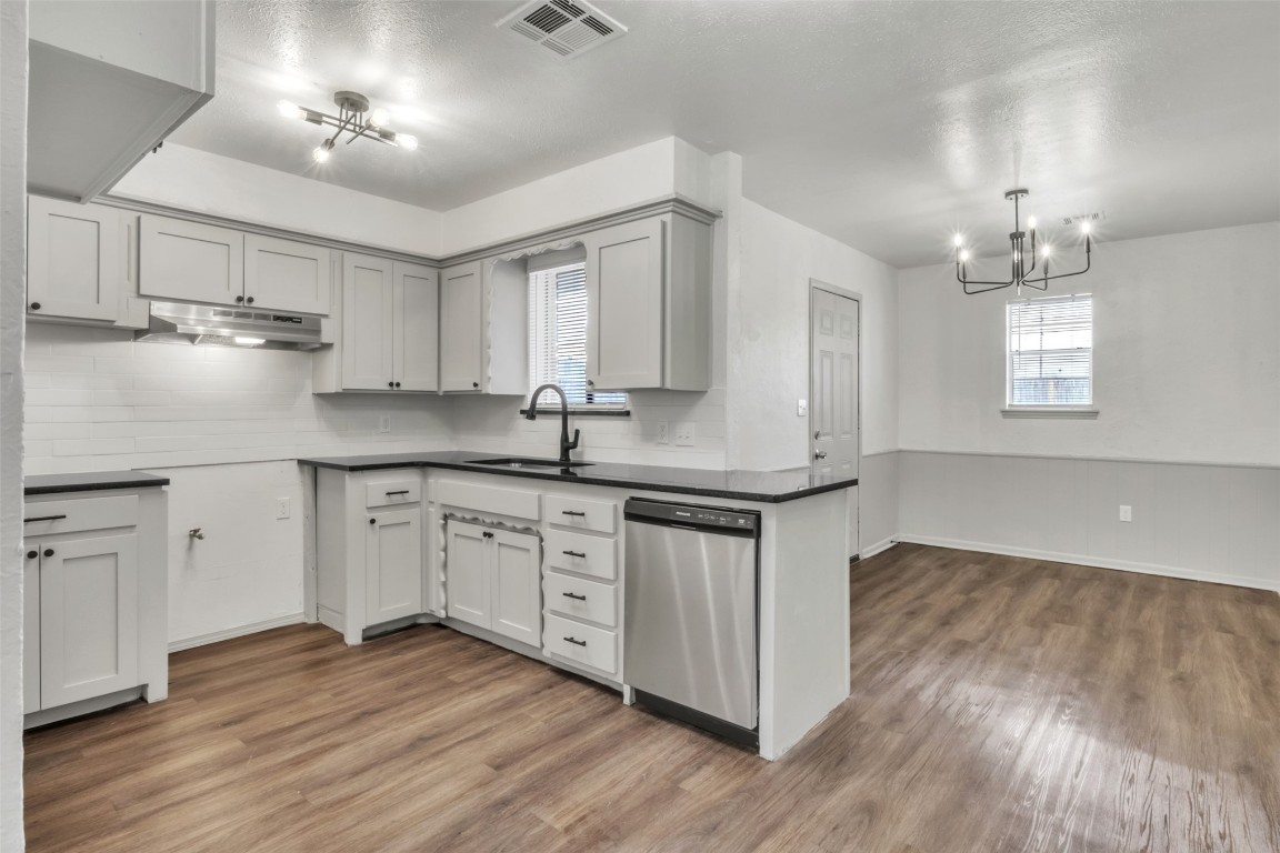 1429 SW 60th Street, Oklahoma City, OK 73159 kitchen with sink, stainless steel dishwasher, a chandelier, dark wood-type flooring, and tasteful backsplash