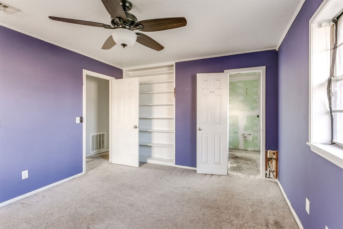 5504 NW 67th Street, Warr Acres, OK 73132 unfurnished bedroom with a textured ceiling, light carpet, and ceiling fan