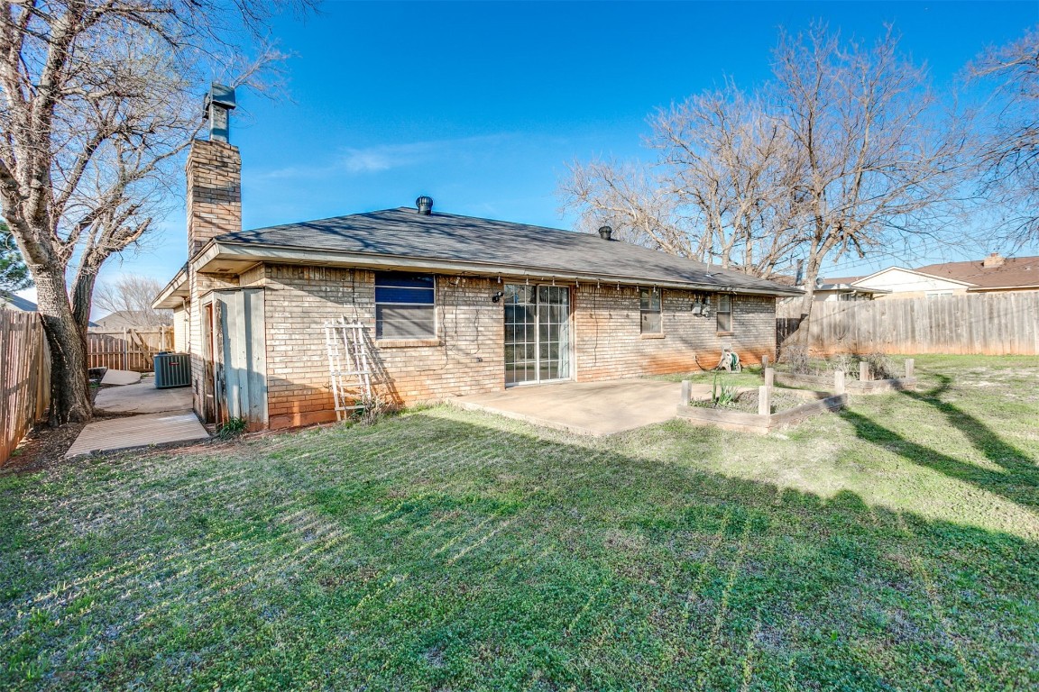 5504 NW 67th Street, Warr Acres, OK 73132 back of property with central air condition unit, a lawn, and a patio