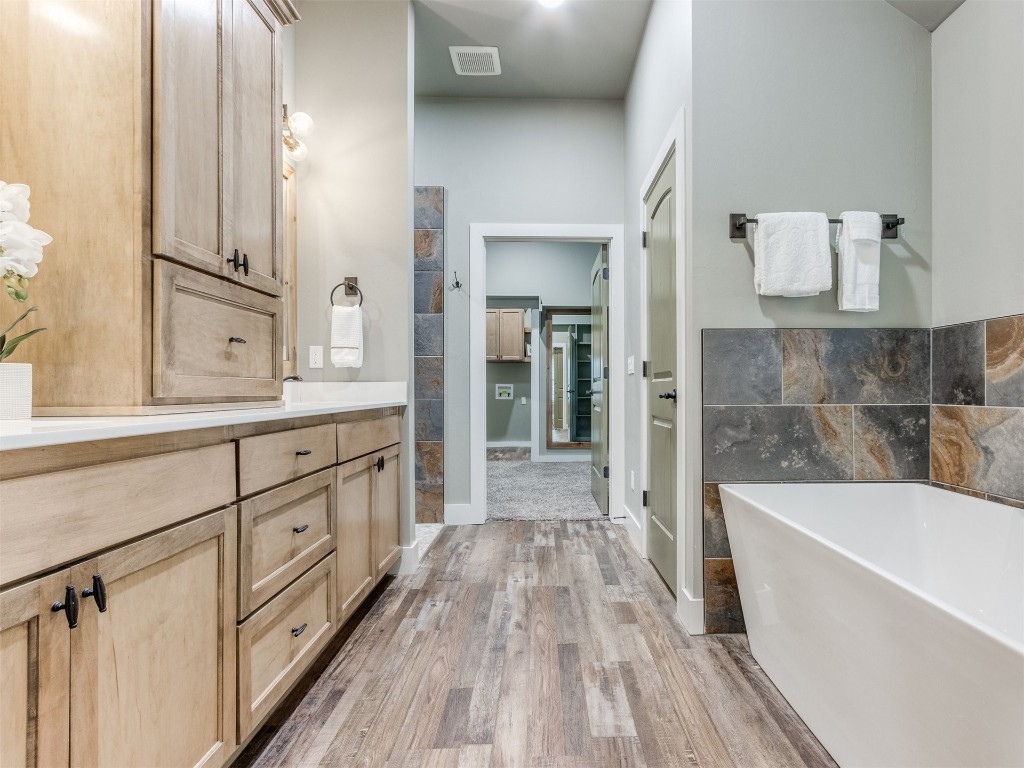 4832 Bermuda Drive, Mustang, OK 73064 bathroom featuring tile walls, a tub, wood-type flooring, and vanity