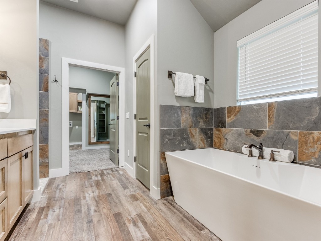 4832 Bermuda Drive, Mustang, OK 73064 bathroom with wood-type flooring, a bath, vanity, and tile walls