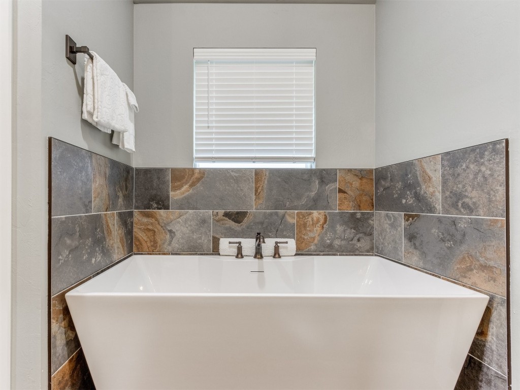 4832 Bermuda Drive, Mustang, OK 73064 bathroom featuring a tub and tile walls