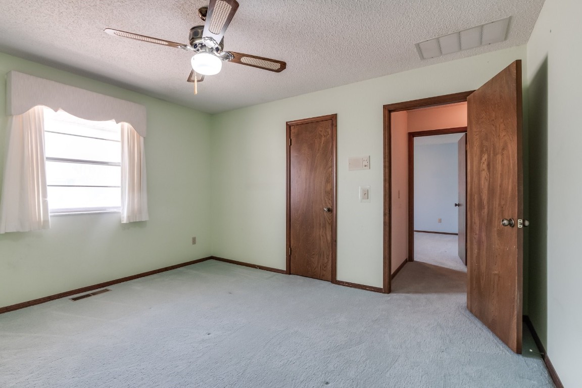 7201 Warriner Way, Oklahoma City, OK 73162 unfurnished bedroom featuring a textured ceiling, light colored carpet, and ceiling fan