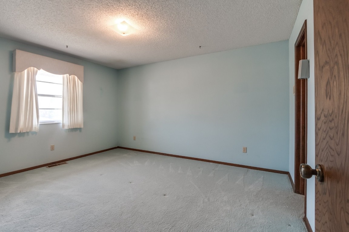 7201 Warriner Way, Oklahoma City, OK 73162 empty room with a textured ceiling and light carpet