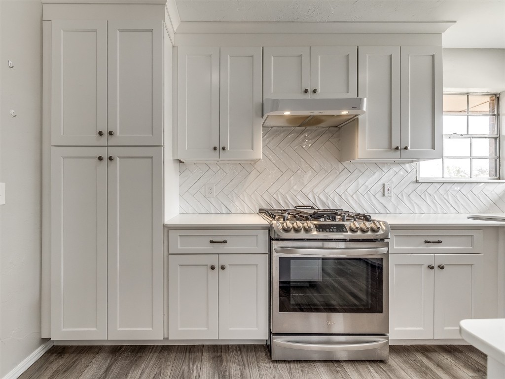 11313 Bluff Creek Drive, Oklahoma City, OK 73162 kitchen with white cabinetry, backsplash, stainless steel gas range, and light hardwood / wood-style flooring