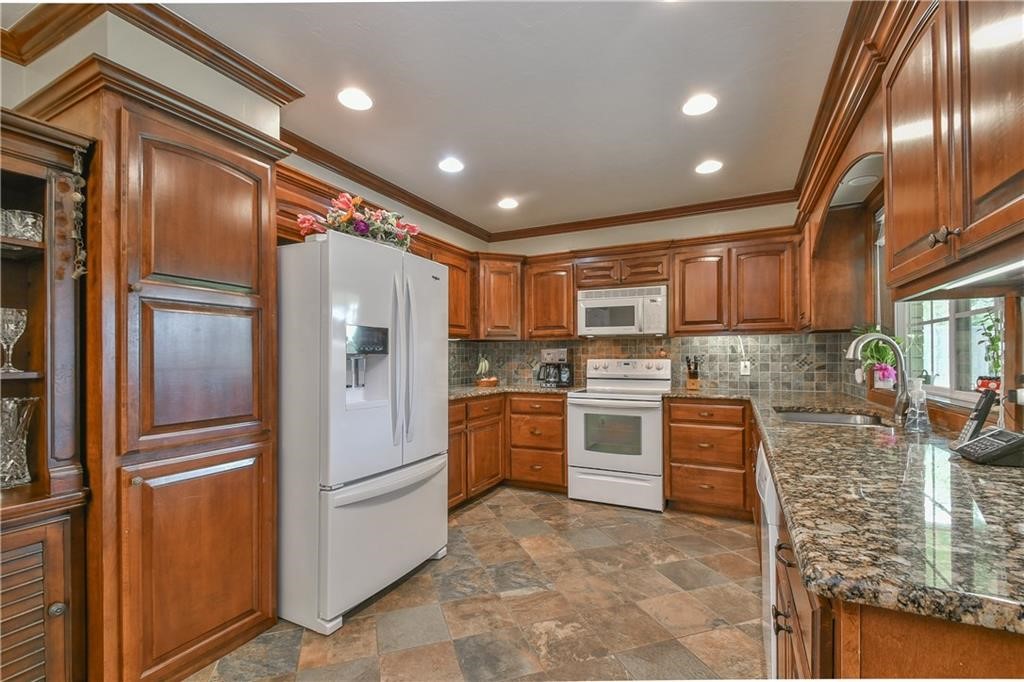 10118 S Kingsgate Drive, Oklahoma City, OK 73159 kitchen with sink, white appliances, tasteful backsplash, and dark tile floors