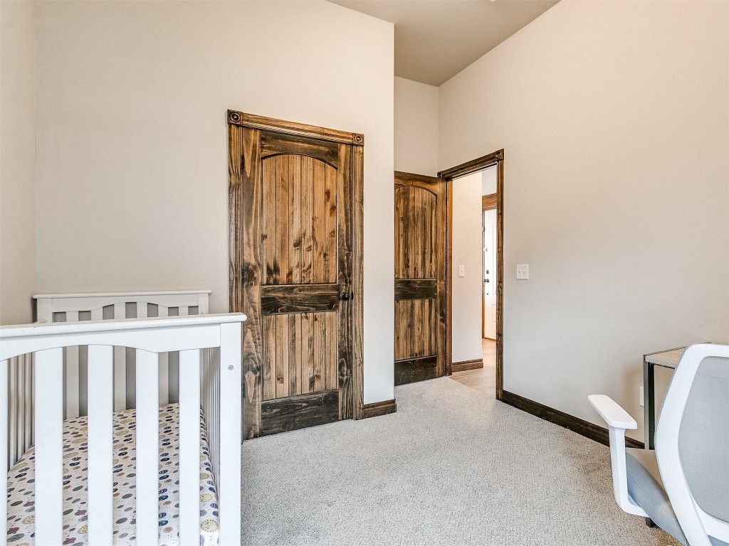 215 Tuscany Circle, Noble, OK 73068 carpeted bedroom featuring a crib and a towering ceiling