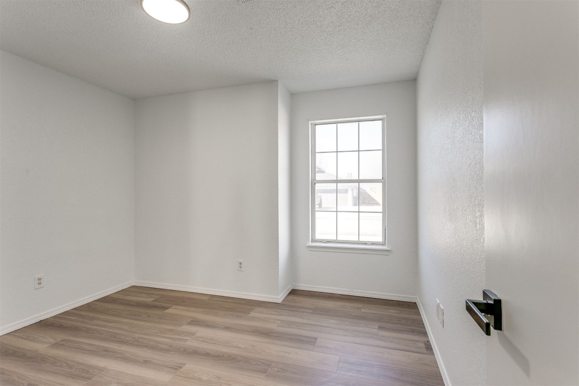 15124 Todd Way, Oklahoma City, OK 73170 empty room featuring a textured ceiling, a wealth of natural light, and light wood-type flooring