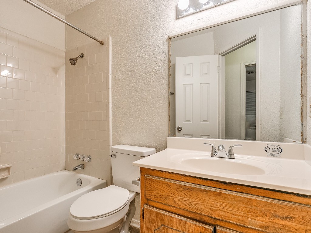 4602 Creek Court, Oklahoma City, OK 73135 full bathroom featuring a textured ceiling, large vanity, toilet, and tiled shower / bath