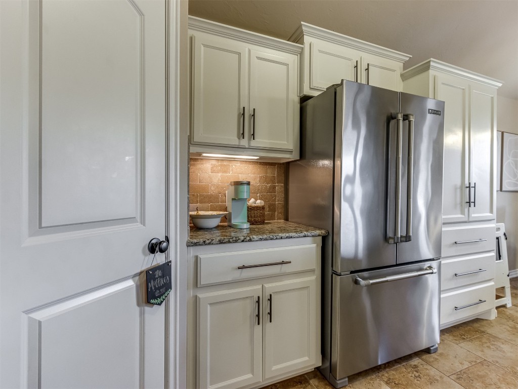 3433 NW 162nd Street, Edmond, OK 73013 kitchen featuring high end fridge, white cabinetry, light tile flooring, dark stone counters, and tasteful backsplash