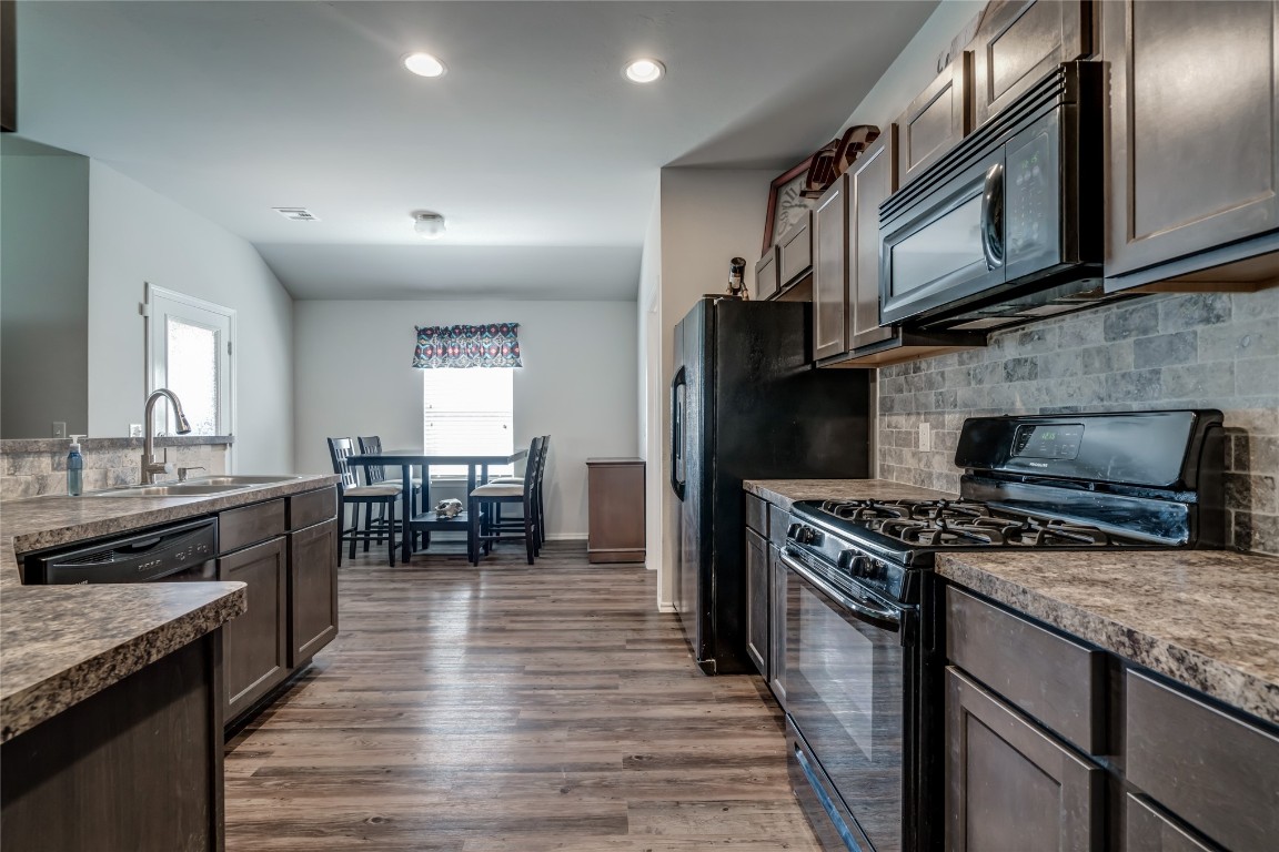 10224 Sussex Place, Oklahoma City, OK 73120 kitchen with tasteful backsplash, hardwood / wood-style floors, black appliances, dark brown cabinetry, and sink