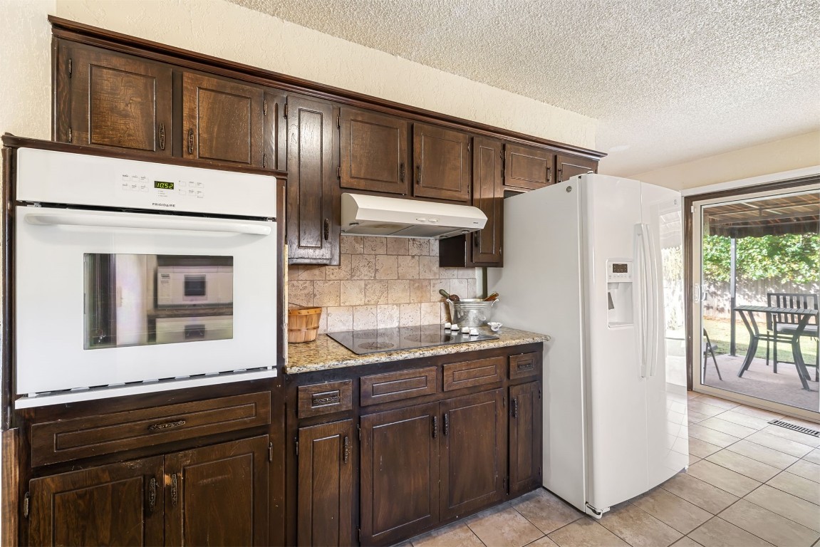 814 Cherrywood Lane, Yukon, OK 73099 kitchen featuring dark brown cabinets, white appliances, and light stone counters