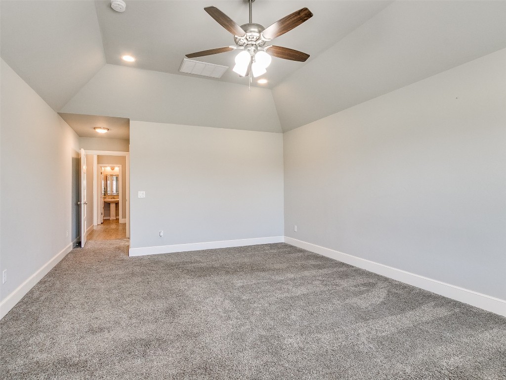 4325 SW 129th Street, Oklahoma City, OK 73173 spare room featuring light carpet, ceiling fan, and vaulted ceiling