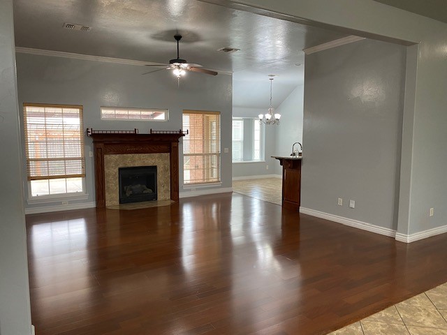 2800 SW 92nd Court, Oklahoma City, OK 73159 unfurnished living room featuring vaulted ceiling, ceiling fan with notable chandelier, light tile flooring, and ornamental molding