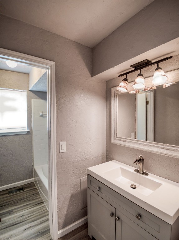 805 S Hwy 76 Highway, Newcastle, OK 73065 bathroom featuring  shower combination, hardwood / wood-style floors, and vanity